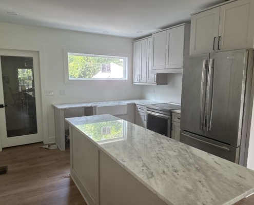 a kitchen with white cabinets and marble counter tops