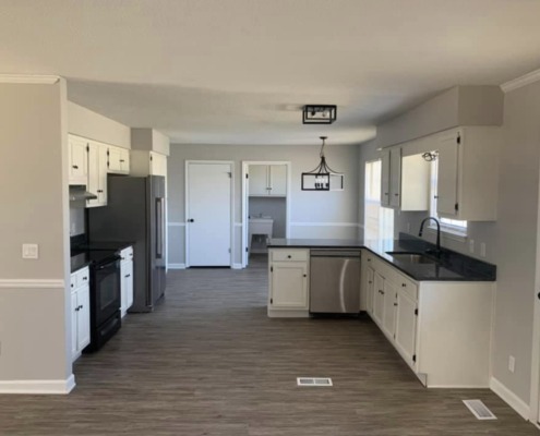 a kitchen with white cabinets and black appliances
