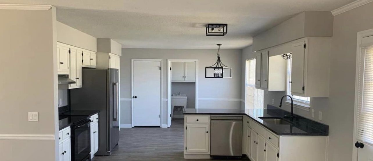 a kitchen with white cabinets and black counter tops