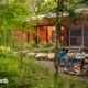 a couple sitting on a bench in front of a fire pit in the woods